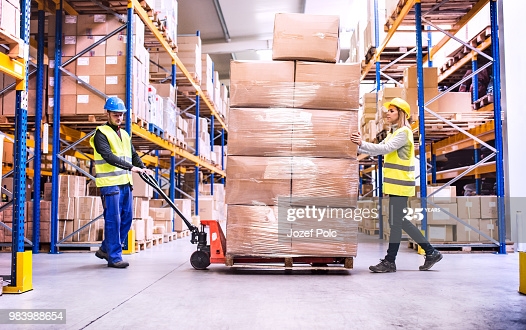 Workers pulling dolly in warehouse